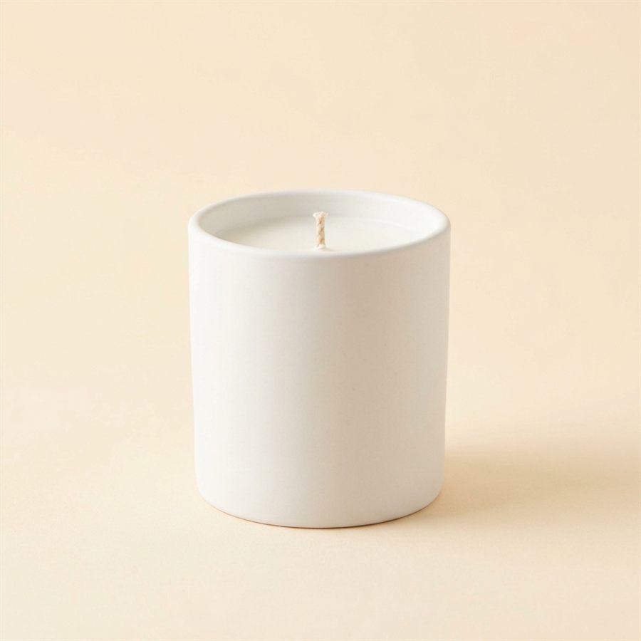 A matte white ceramic jar candle